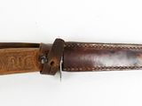 brown leather belt with engraved design on it on a white surface