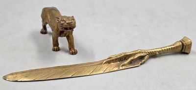 figurine en laiton représentant un tigre et une plume posée sur une table