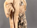 statue of a man with a robe and a hat on a marble base