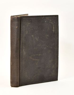 an old book sitting on top of a white table next to a white wall
