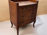 une petite commode en bois posée sur un sol blanc