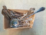 une boîte remplie de cuillères en argent et des cuillères posées sur une table