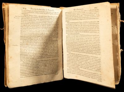 un vieux livre ouvert, dévoilant une page de texte sur fond noir
