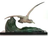 statue représentant un oiseau volant au-dessus d'une vague sur fond blanc