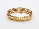 a close up of a gold bracelet on a white surface