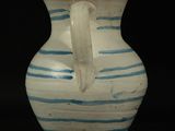 a white vase with blue stripes on it on a black background