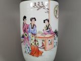 a white vase with a painting on it sitting on a table