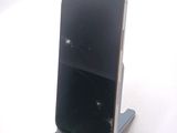a broken cell phone sitting on a stand on a white surface