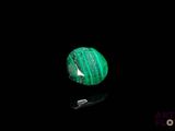a close up of a green stone on a black surface
