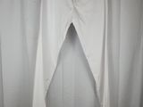 a pair of white pants hanging on a hanger in front of a curtain