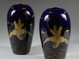 une paire de vases bleus ornés de motifs dorés sur fond blanc