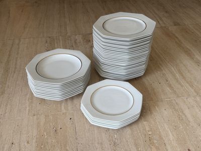 plusieurs assiettes blanches empilées les unes sur les autres sur un plancher en bois