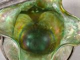 a green glass bowl with a silver handle on a table