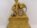 a gold clock with a statue on top of it