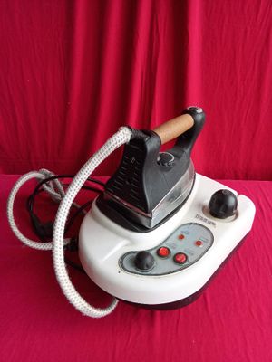 a white and black steam iron on a red surface