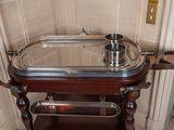 a silver tray on a wooden stand in the corner of a room
