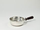 une casserole argentée avec un manche en bois posée sur une surface blanche