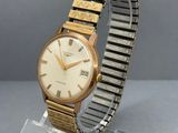 a close up of a gold and silver wrist watch on a clear stand