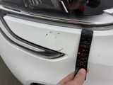 a hand that is holding a ruler near a car ' s hood