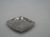 a small silver plate on a table with a white background