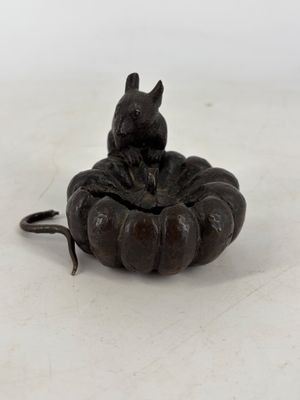 une petite statue représentant un chat assis sur une citrouille