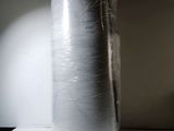 a white vase that is wrapped in plastic on a shelf