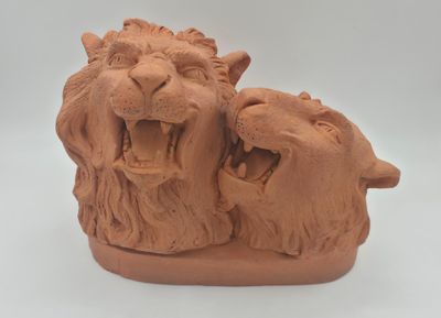 une sculpture en argile représentant deux lions la gueule ouverte