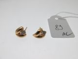 une paire de boucles d'oreilles en or et diamants posée sur une table blanche
