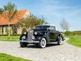 a vintage car parked on a cobblestone road in front of a house