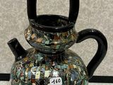 un vase noir et vert posé sur une table