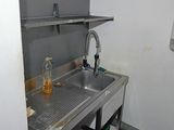 un évier dans un coin d'une cuisine où le sol est encombré d'objets divers