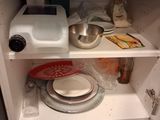 a small cabinet with a microwave and dishes inside of it