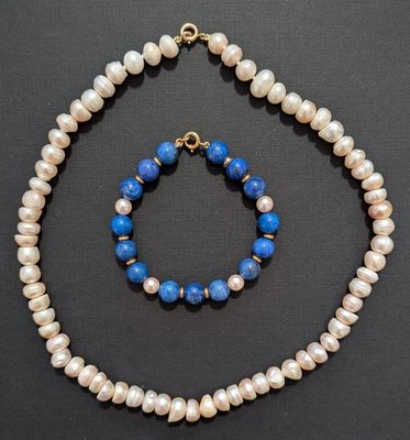 a close up of a necklace and bracelet on a black surface