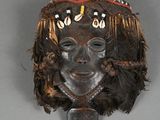 an image of a wooden mask with feathers on it