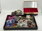 une boîte noire remplie de bijoux variés, posée sur une surface blanche