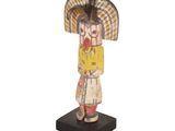 an image of a wooden statue of a woman with a hat on her head