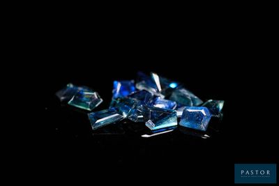 blue crystals are scattered on a black surface with a black background