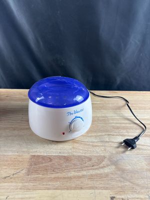 un chauffe-cire blanc et bleu posé sur une table en bois