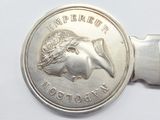 a silver key with a coin on it on a white surface