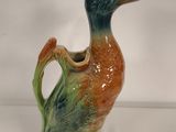 a ceramic duck that is sitting on a white surface