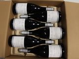 six bottles of wine in a cardboard box on a table