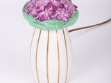 un vase blanc contenant des fleurs violettes, posé sur une table
