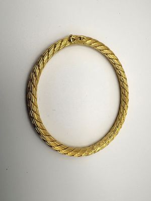 gros plan d'un bracelet en or sur une surface blanche