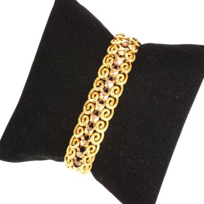 un gros plan d'un bracelet plaqué or posé sur un coussin noir