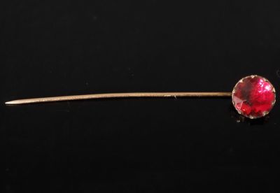 un gros plan d'une pierre rouge fixée sur un bâton, posée sur une surface noire