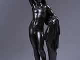 une statue noire représentant une femme tenant un sac à main posée sur une table