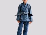 the boy is wearing a blue karate suit and holding a black belt