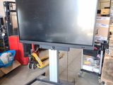 a large flat screen tv sitting on a stand in a warehouse
