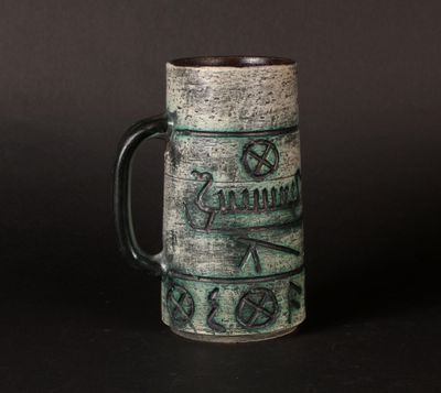 a green mug with writing on it sitting on a table