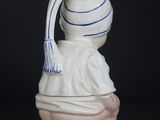 a white vase with a blue and white hat on top of it